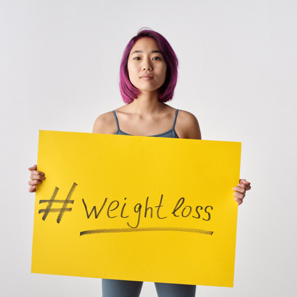 Adult holding a sign promoting metabolic wellness and healthy weight management as part of a broader MICC IM wellness plan.